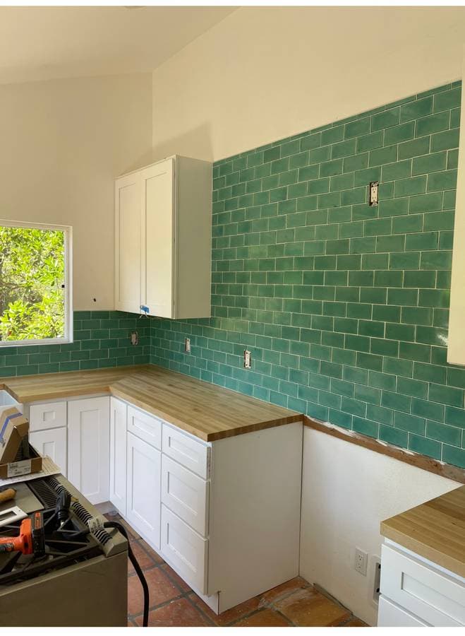 picture of custom kitchen remodel with green tile backsplash and wood countertops with new white cabinets